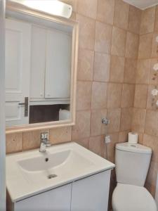 a bathroom with a sink and a toilet and a mirror at F2 Central Luxury Apartment in Volos