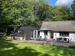 ein kleines schwarzweißes Haus mit einem Tisch und Stühlen in der Unterkunft Bokis - Modern Forest Cottage in Brösarp