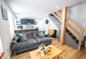 a living room with a gray couch and a staircase at The Old Coach House in Aberaeron