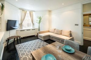 uma sala de estar com um sofá e uma mesa em Spacious 1 bedroom / Gloucester Road / Harrods em Londres