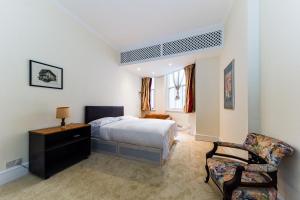 a bedroom with a bed and a chair at HydePark Queens Gate Apt in London