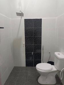 a bathroom with a white toilet and a black tile wall at Inara Homestay Besut in Jertih