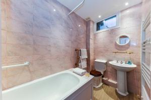 a bathroom with a tub and a sink and a toilet at HydePark Queens Gate Apt in London