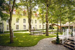 ein großes weißes Gebäude mit Bäumen im Hof in der Unterkunft Schlosshotel Neufahrn in Neufahrn in Niederbayern