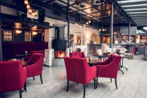 un restaurante con sillas, mesas y chimenea en Schlosshotel Neufahrn en Neufahrn in Niederbayern