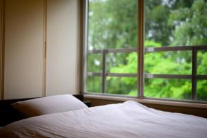 岡山的住宿－円山山荘 ～自然と調和し和の美を感じる至福の宿～，一间卧室设有一张床和一个大窗户
