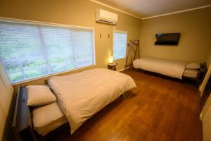 a small bedroom with two beds and a window at 円山山荘 ～自然と調和し和の美を感じる至福の宿～ in Okayama