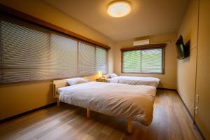 two beds in a room with two windows at 円山山荘 ～自然と調和し和の美を感じる至福の宿～ in Okayama