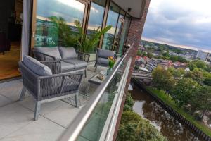 奧爾登堡的住宿－CABANA - TheView - 10th Floor - Terrasse - Waterfront - Hafenviertel，阳台配有椅子,享有河景