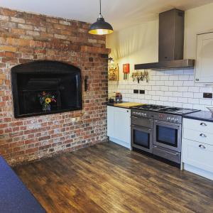 uma cozinha com uma parede de tijolos e um forno em The Cob House. em Ifton Heath
