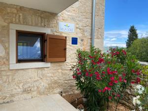 a building with a window and a bush with pink flowers at Villa Sole in Rakalj