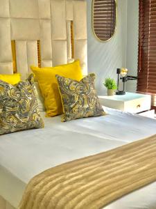 a bed with yellow and white pillows on it at The Oasis in Hartbeespoort
