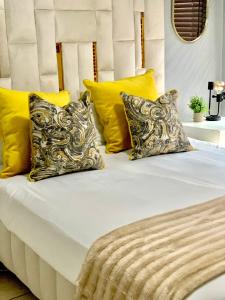a bed with yellow and white pillows on it at The Oasis in Hartbeespoort