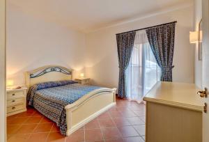 a bedroom with a bed and a dresser and a window at Villas with air conditioning and private outdoor area just a few minutes from La Pelosa in Cuile Pazzoni