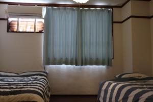 a bedroom with two beds and a window at Apartment Namba Daikoku in Osaka