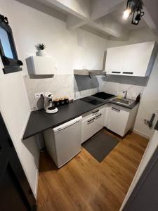une petite cuisine avec des placards blancs et un comptoir noir dans l'établissement La maison d’Hélèna, à Montauban