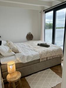 a bedroom with a large bed with a view of the water at Surla Houseboat De Saek with tender in Monnickendam