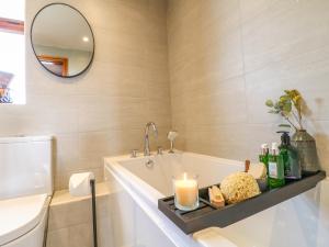 een badkamer met een bad met een kaars en een spiegel bij Rowtor in Matlock