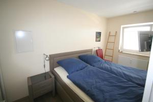 1 dormitorio con cama con sábanas azules y ventana en Miramar App 708 inkl WLAN, en Grömitz