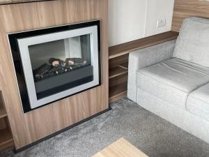 a living room with a fireplace next to a couch at 8 Berth Static Caravan - Holiday Resort Unity Brean in Berrow