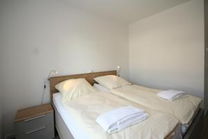 una camera con due letti con lenzuola e asciugamani bianchi di Haffkamp 21a Whg 3 inkl WLAN a Grömitz
