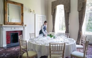 a woman standing in front of a table with wine glasses at Bailbrook House Hotel, Bath in Bath