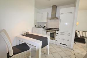 - une cuisine blanche avec une table et des chaises dans l'établissement Residenz am Kurpark App 10 inkl WLAN, à Grömitz