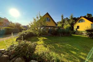 a yellow house on a grassy yard with a house at Ferienhaus Dresdner Weg 16 in Loddin