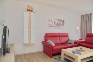 ein Wohnzimmer mit einem roten Sofa und einem Tisch in der Unterkunft Miramar App 705 inkl WLAN in Grömitz