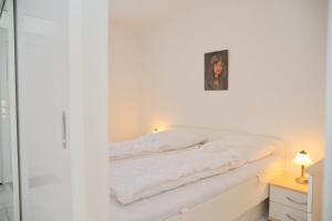 1 cama blanca en un dormitorio con una foto en la pared en Grömitz- Center I App 540 inkl WLAN, en Grömitz