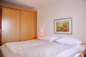 een slaapkamer met een bed en een schilderij aan de muur bij Haus Belvedere App 69 WLAN inkl in Grömitz