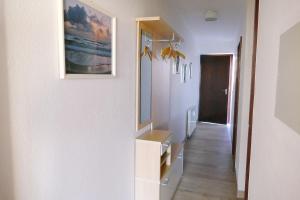 un couloir avec un mur blanc et une photo sur celui-ci dans l'établissement Haus Belvedere App 34 WLAN inkl, à Grömitz