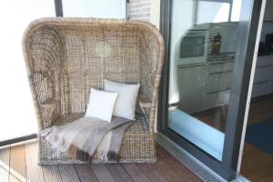 een rieten stoel met een kussen op een balkon bij Seeblick Seeloft 2 inkl WLAN in Grömitz