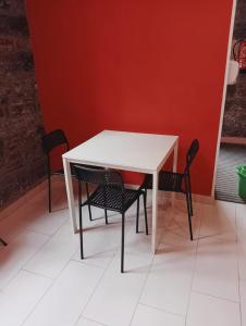 une table blanche avec deux chaises et un mur rouge dans l'établissement Albergue de Peregrinos Villa de Luarca, à Luarca