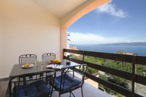 a table and chairs on a balcony with a view of the ocean at Apartment Gino in Ravni