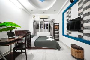 een slaapkamer met een bed, een bureau en een televisie bij Ohio Hotel & Apartment in Ho Chi Minh-stad