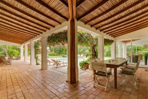une terrasse avec une pergola en bois, une table et des chaises dans l'établissement Villa Jardim do Paraiso, à Mexilhoeira Grande