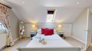 a bedroom with a large white bed with red pillows at Spring Hill Cottage in Bladon