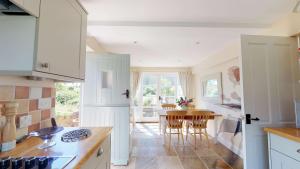 uma cozinha com armários brancos e uma mesa com cadeiras em Spring Hill Cottage em Bladon