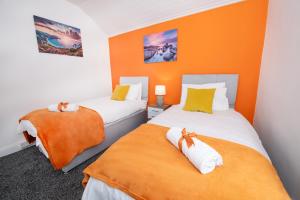 two beds in a room with orange walls at Versatile Cozy & Spacious Comfort Hull Apartments in Hull