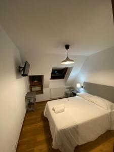 1 dormitorio con 1 cama blanca y TV en EL TRASTERO DE PALMERO, en A Coruña