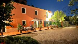 un bâtiment orange avec des tables, des chaises et des parasols dans l'établissement Agriturismo Podere Marchiano, à Larciano