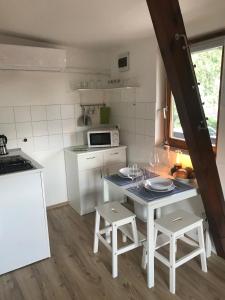 a kitchen with a table and two stools at Lovas Udvarház Ezüst Zabla Apartman Piliscsaba in Piliscsaba