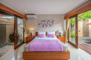 a bedroom with a large bed with pink pillows at Nyanyi Sanctuary Villa by Ini Vie Hospitality in Tanah Lot