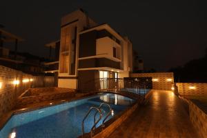 a villa with a swimming pool at night at Casa Lola in Lonavala