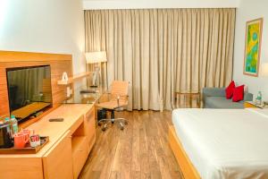 um quarto de hotel com uma cama e uma secretária com uma televisão em Courtyard by Marriott Gurugram Downtown em Gurgaon
