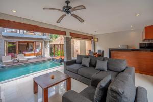 a living room with a couch and a swimming pool at Nyanyi Sanctuary Villa by Ini Vie Hospitality in Tanah Lot
