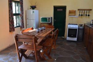 Lindy's Guesthouse في ماسيرو: مطبخ مع طاولة خشبية مع كراسي وثلاجة