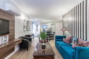 Romney Park Luxury Apartments في كيب تاون: غرفة معيشة مع أريكة زرقاء وطاولة