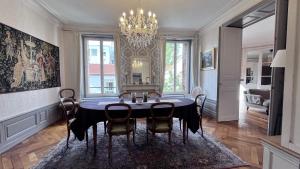 a dining room with a table with chairs and a chandelier at Résidence de la Marquise in Nancy